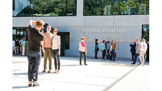 Studierende machen Fotos vor dem ZF Campus der ZU 