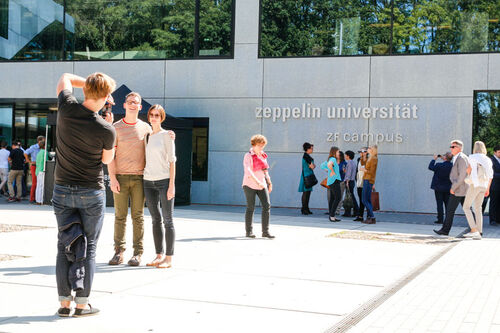 Studierende machen Fotos vor dem ZF Campus der ZU